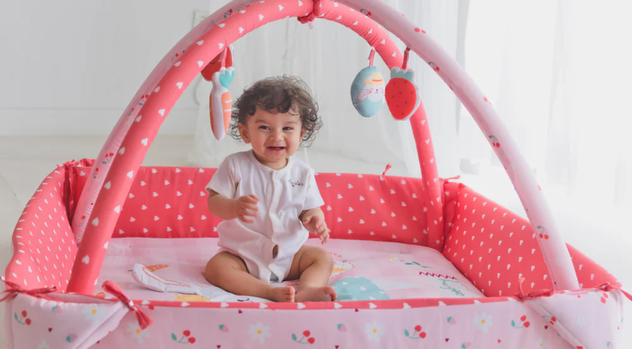 A kid is sitting and playing in a colorful play mat