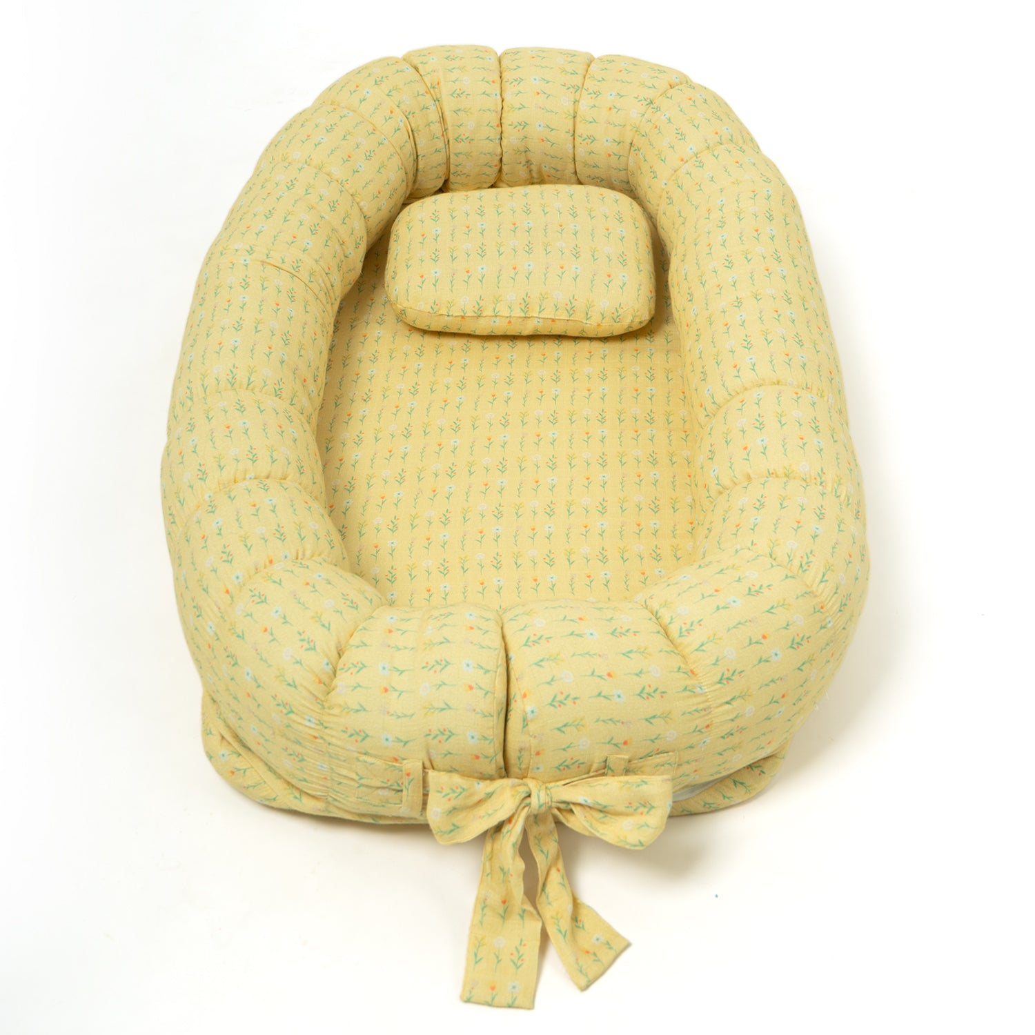 A yellow-colored baby lounger with a soft, quilted pattern, featuring a padded oval shape and an attached pillow.