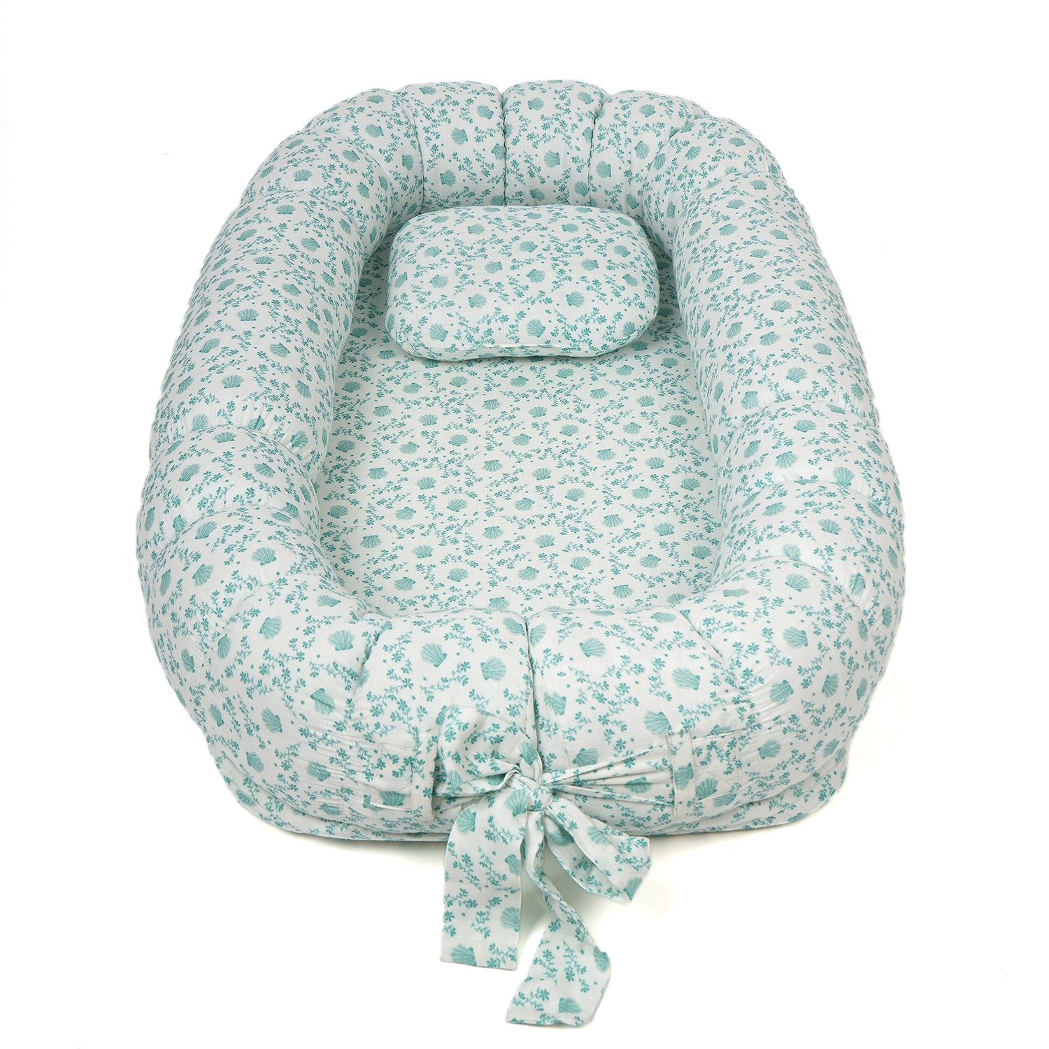 Baby nest bed with a soft cushion and a light blue floral print, featuring a tied bow at the bottom for adjustability.