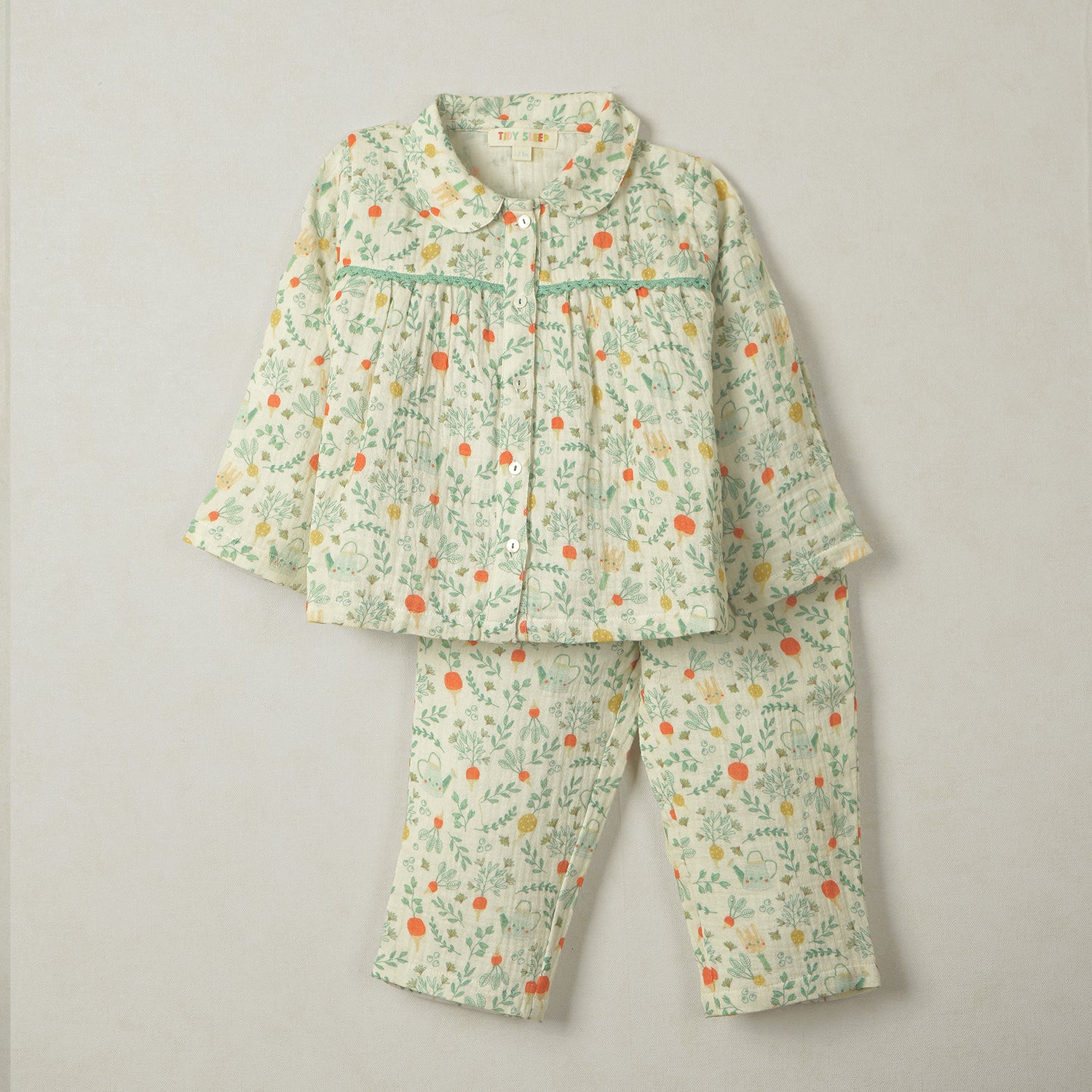 Cream-colored baby pajama set with a botanical floral print, featuring a button-up top with a Peter Pan collar and matching pants.