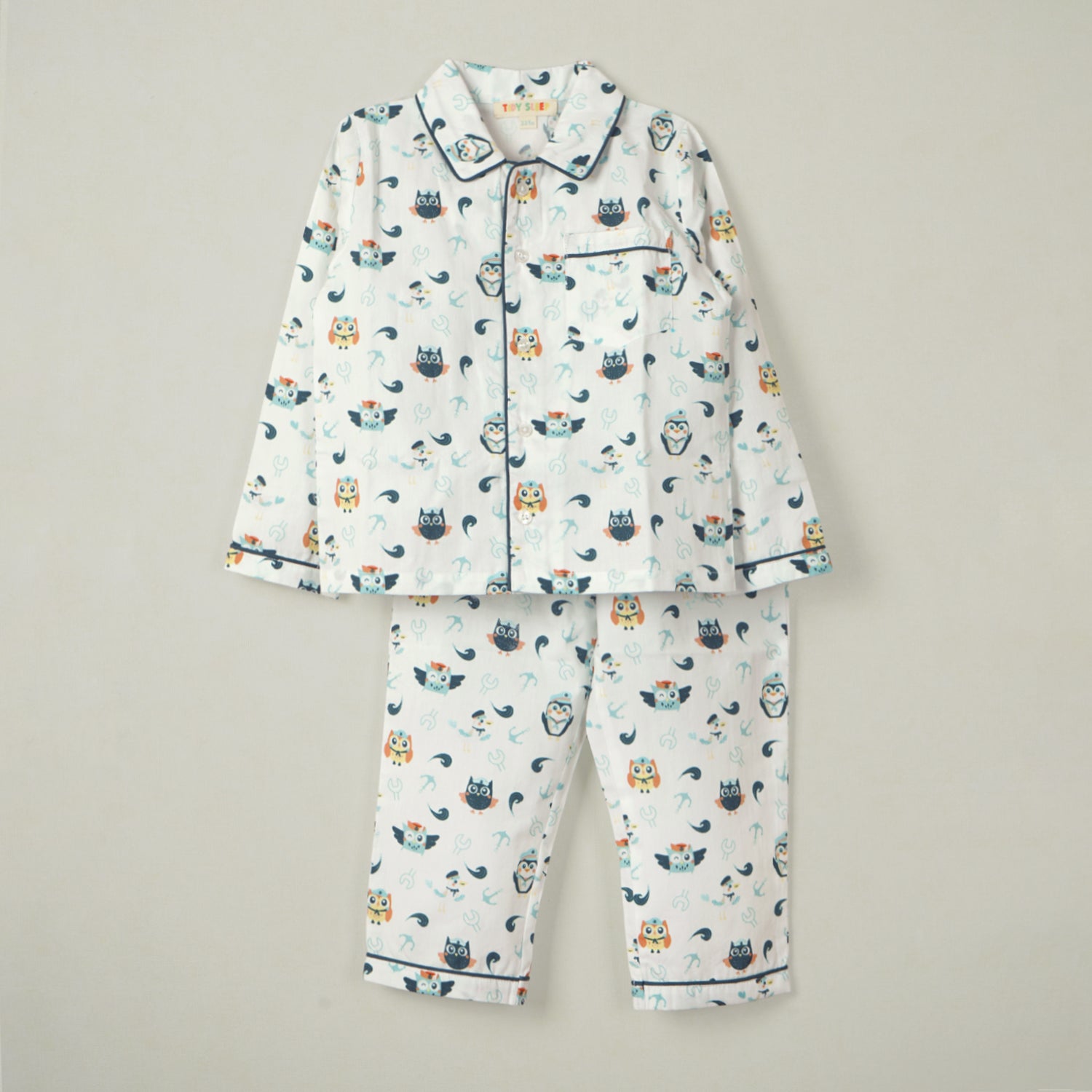 White baby pajama set with an owl print, featuring a button-up shirt with a collar and matching pants, displayed on a neutral background.